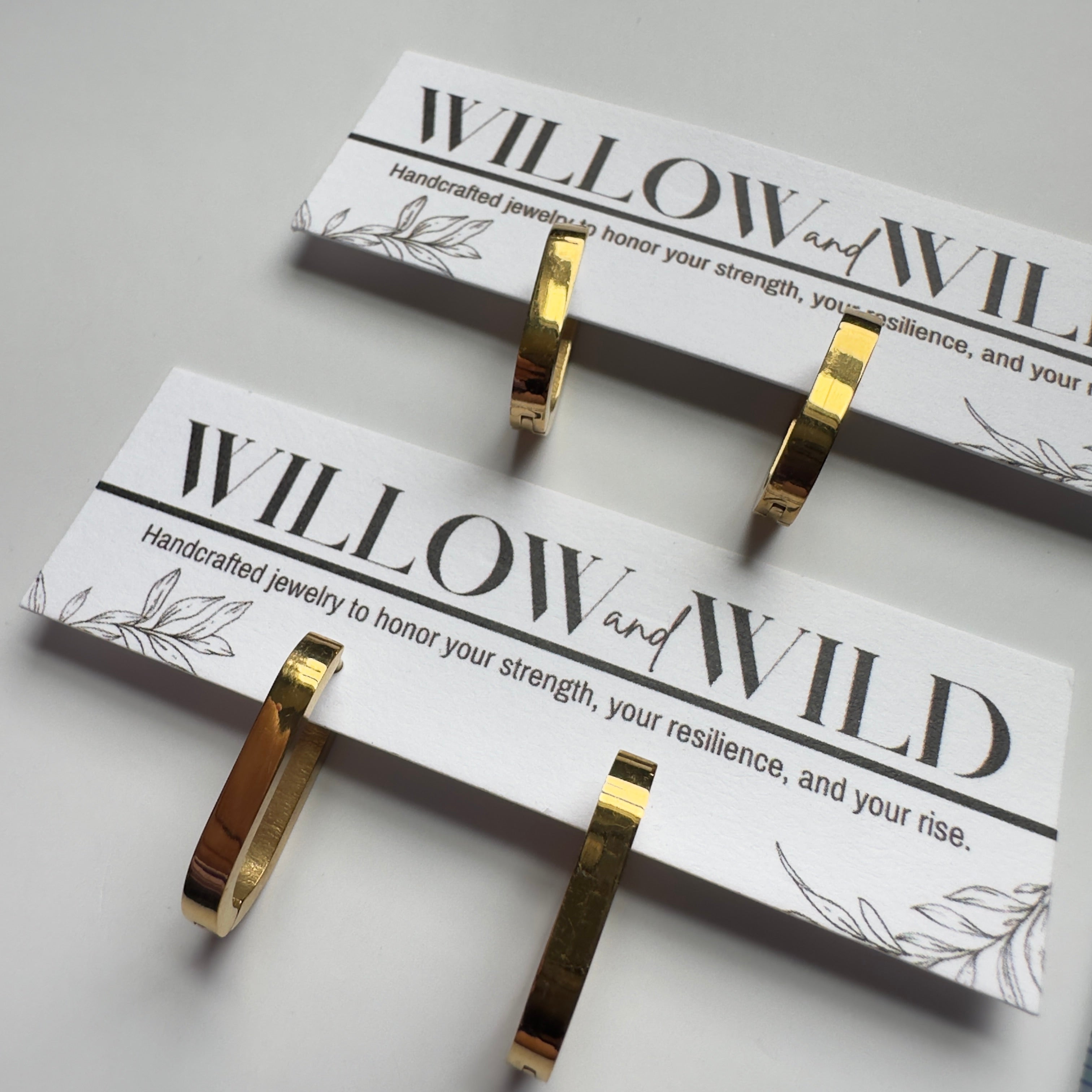 Four gold hoop earrings displayed on white branded cards labeled WILLOW and WILD, photographed on a light gray background.